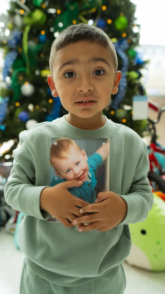 A child holding a photograph of a younger child.