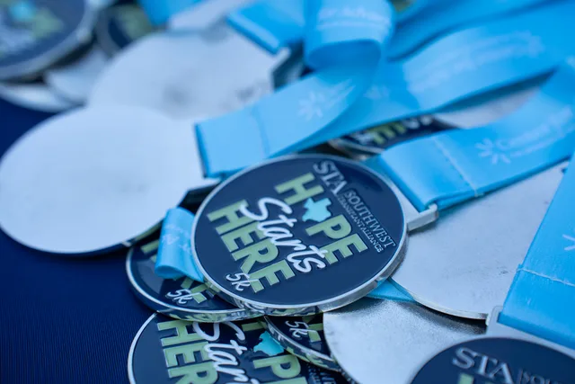 Hope Starts Here 5K medals with blue ribbons